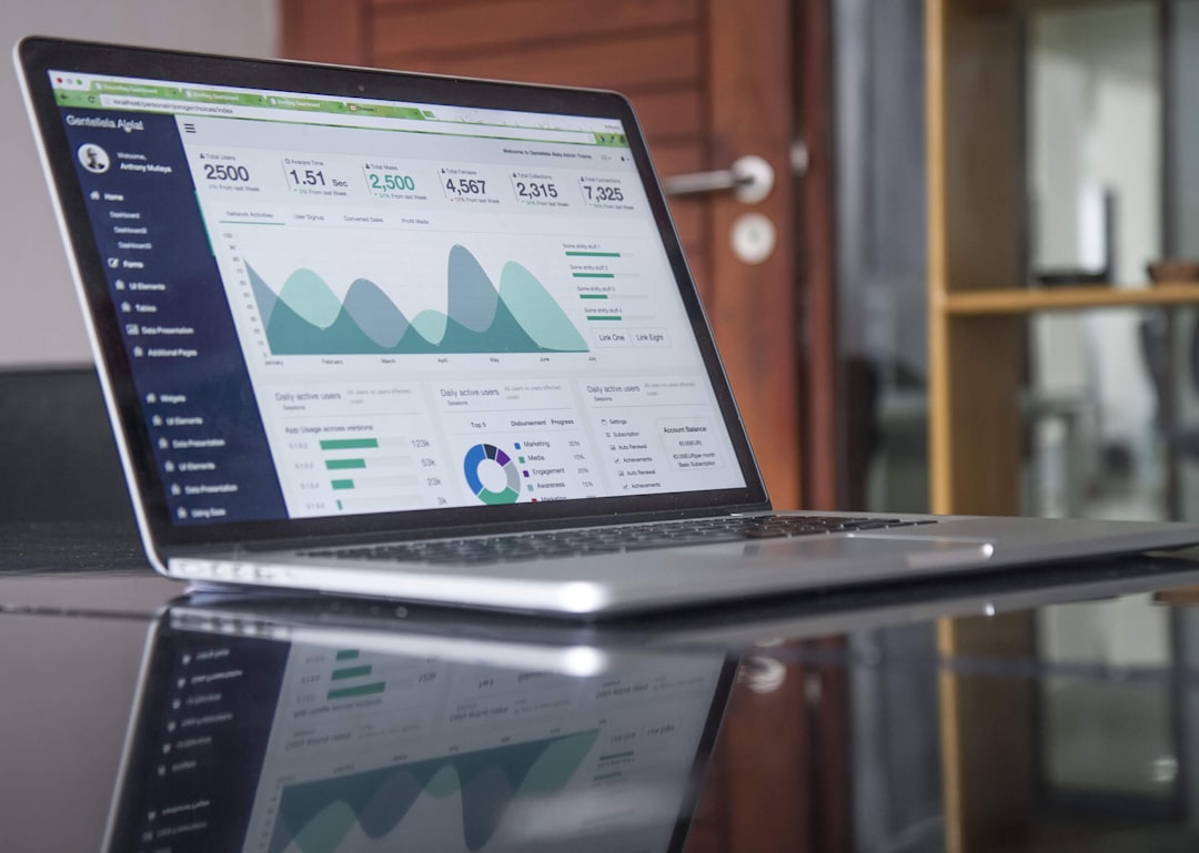 A laptop on a glass table displaying marketing analytics charts and performance metrics