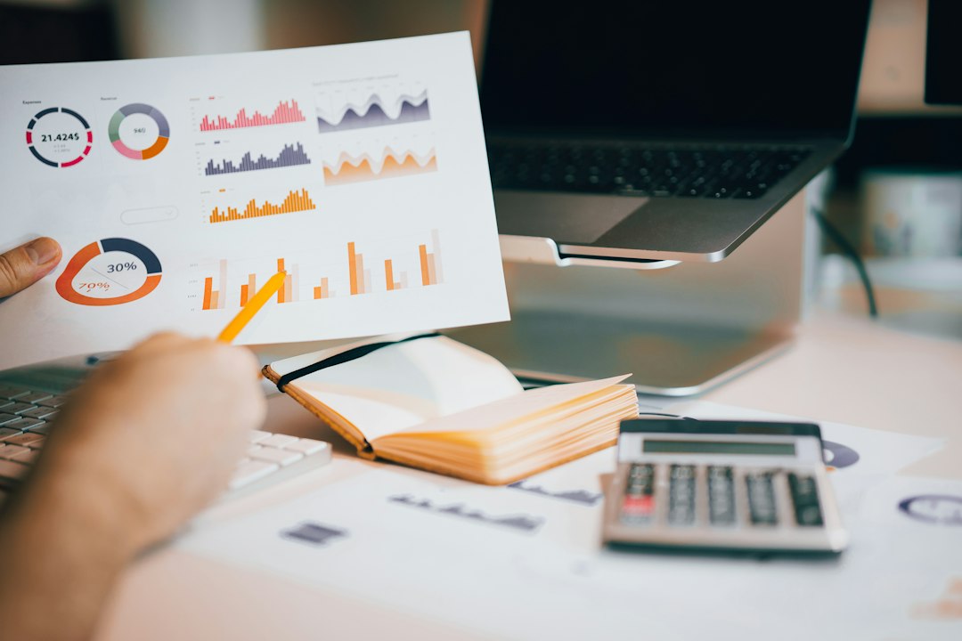 A person holding a printed report over a laptop while reviewing marketing results